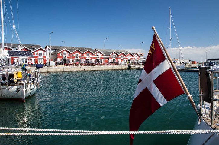 Pohled na přístavní město Skagen s typickými  červenými dřevěnými dánskými stavbami a loděmi. Dánská vlajka v předu